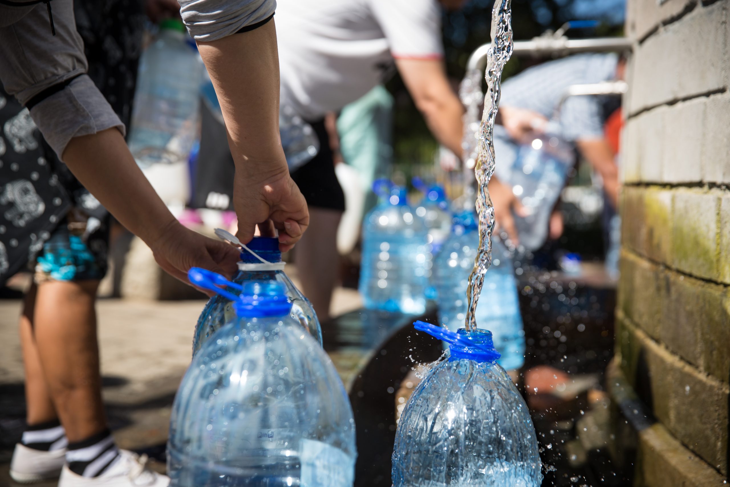 People collecting spring water in plastic bottles