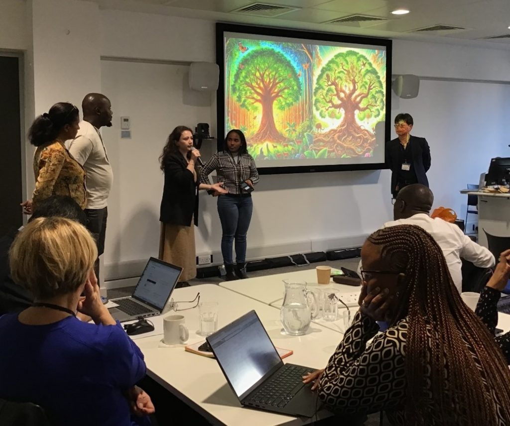 A woman is speaking and giving a presentation with her team members looking on. 