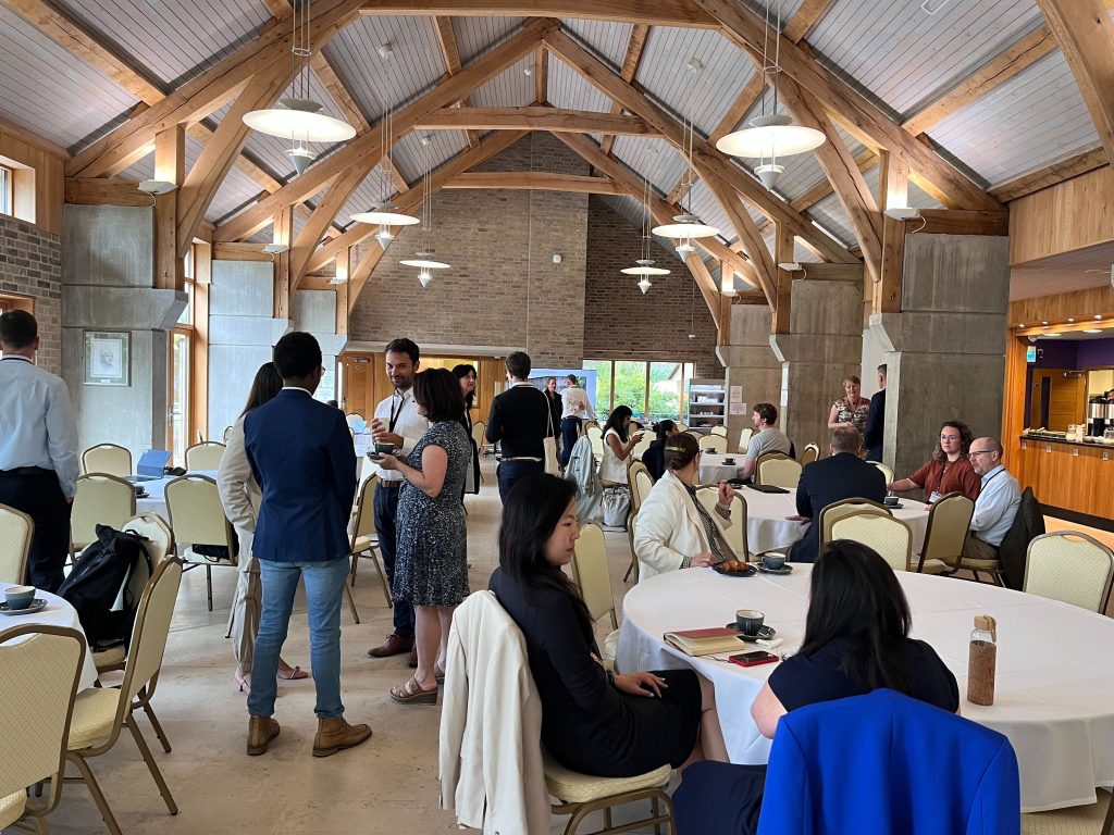 A room with people gathered round tables and standing in small groups talking