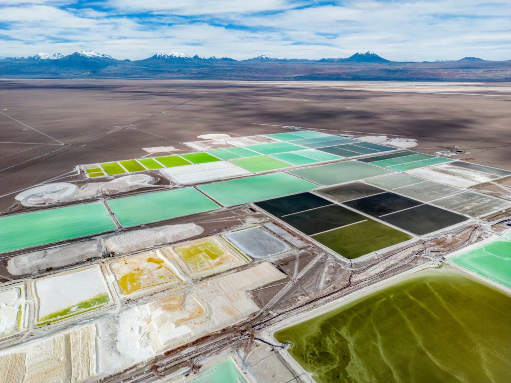 An aerial photo showing a desert with large turquoise and lime green pools laid out in grids